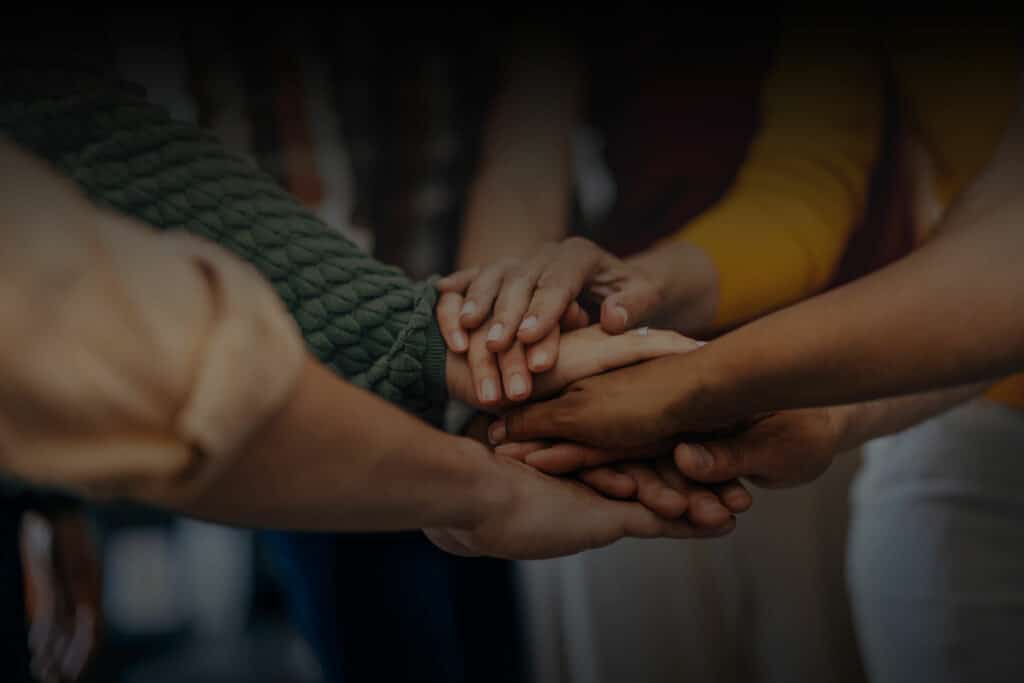 People in a circle with their hands in the middle