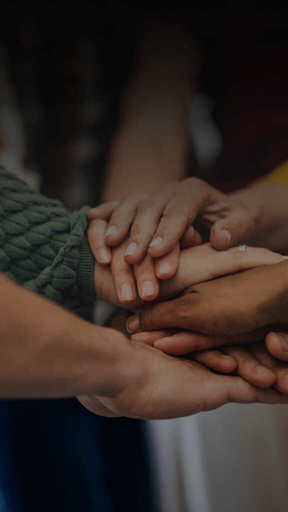 People in a circle with their hands in the middle